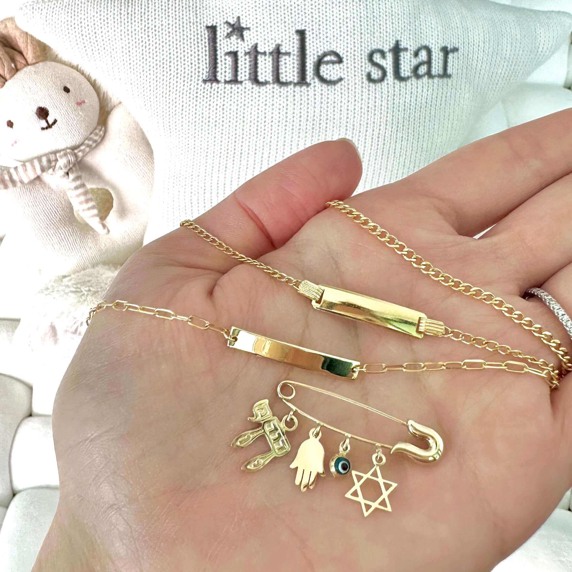 Hand holding Little Star gold jewelry with delicate charms and chains