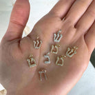 Hand displaying a selection of small, elegant gold and silver jewelry charms from our brand collection.