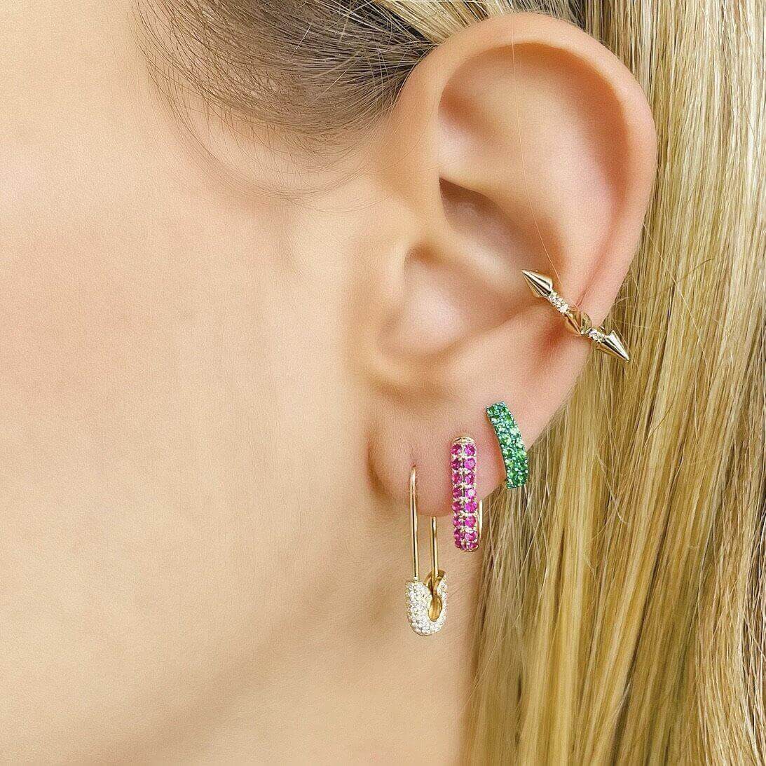 Model with multi-colored gemstone hoop earrings and gold arrow ear cuff from [Brand Name]'s jewelry collection.