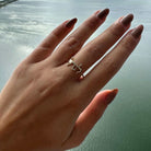 Hand wearing an elegant silver ring with unique design by the water, showcasing our finest jewelry collection.