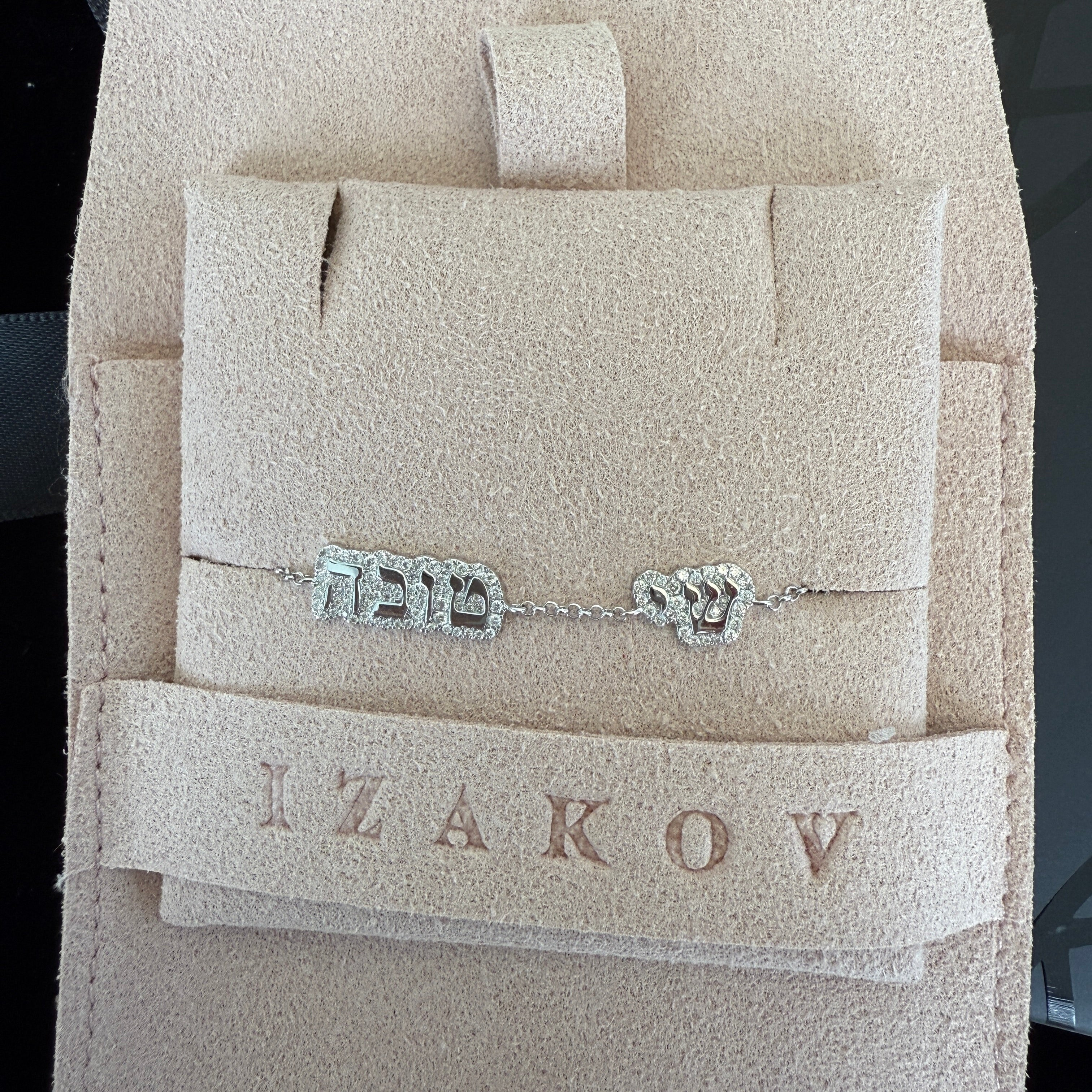 14K gold personalized bracelet in Hebrew, displayed in soft pouch with brand name Izakov, showcasing diamond-encrusted nameplate.