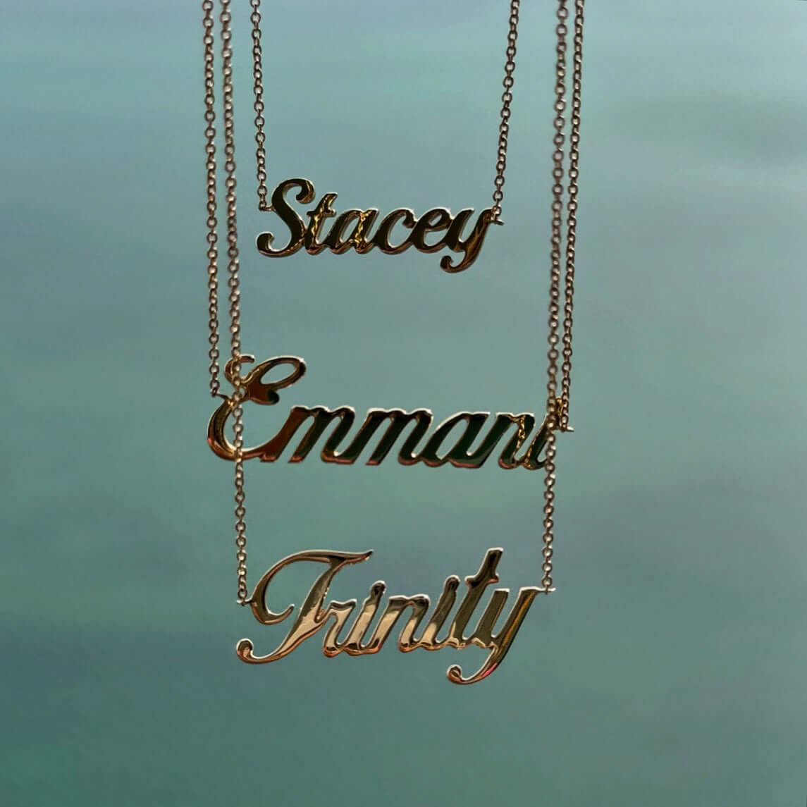 14K gold personalized script nameplate necklaces featuring the names Stacey, Emmart, and Trinity. Elegant and custom accessories.