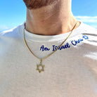 Man wearing gold Star of David necklace with "Am Israel Chai" shirt against a clear blue sky background.