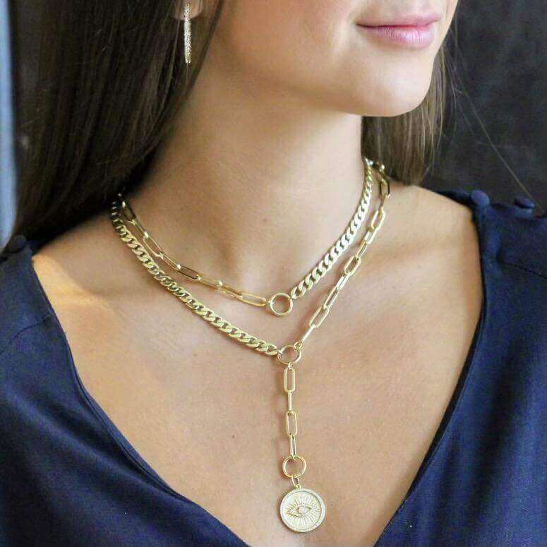 Woman wearing layered gold chain necklaces featuring an engraved pendant from our luxury jewelry collection.