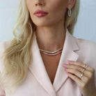 Woman showcasing elegant jewelry including hoop earrings, layered necklaces, and delicate rings from our exclusive jewelry collection.