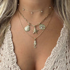 Woman wearing layered gold necklaces with seashell, starfish, sand dollar, and seahorse pendants from our jewelry collection