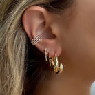 Close-up of a woman's ear adorned with multiple gold and diamond earrings, showcasing a stylish and elegant ear stack.