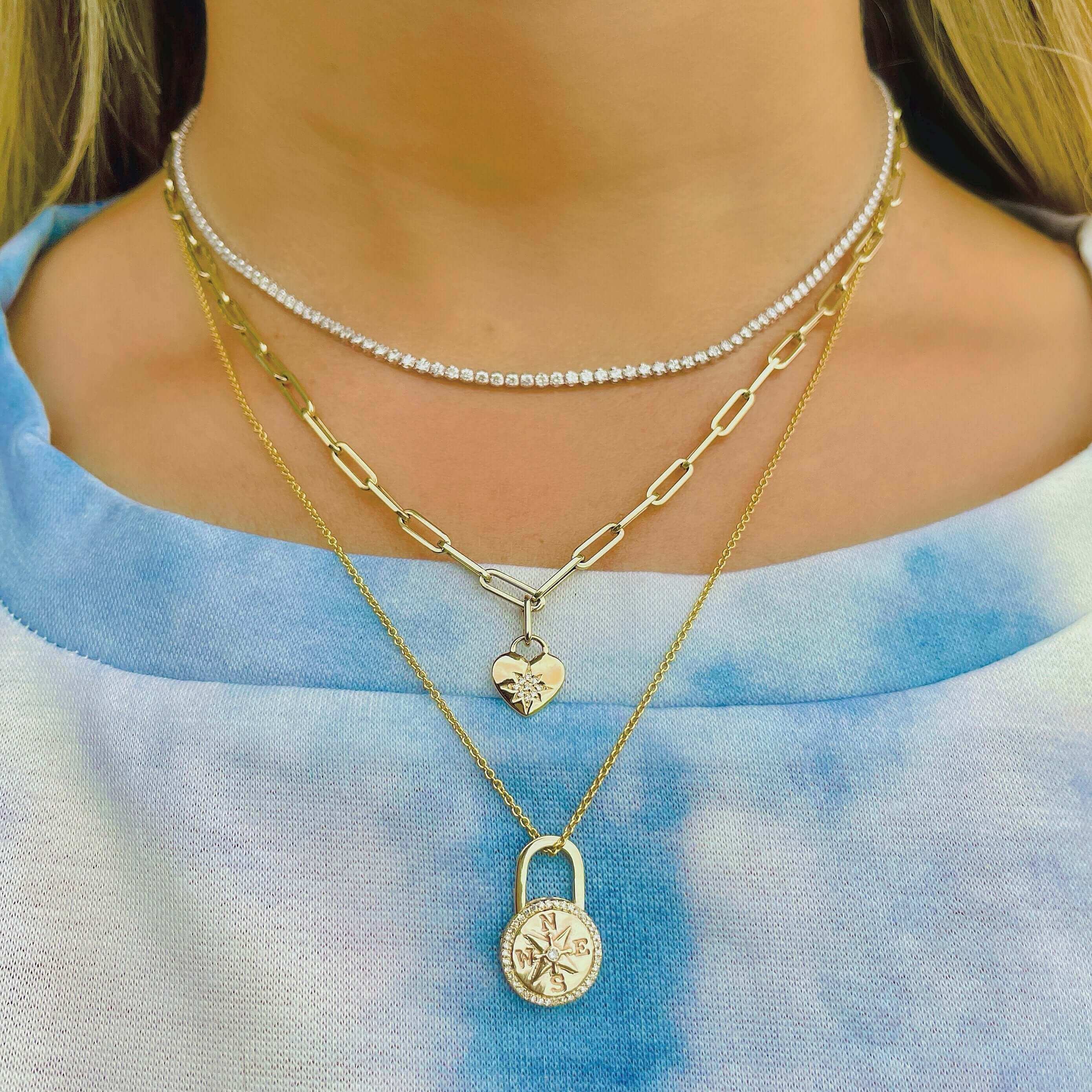 Layered gold necklaces with lock and heart pendants from our jewelry brand, perfect for adding a stylish and unique touch to any outfit.