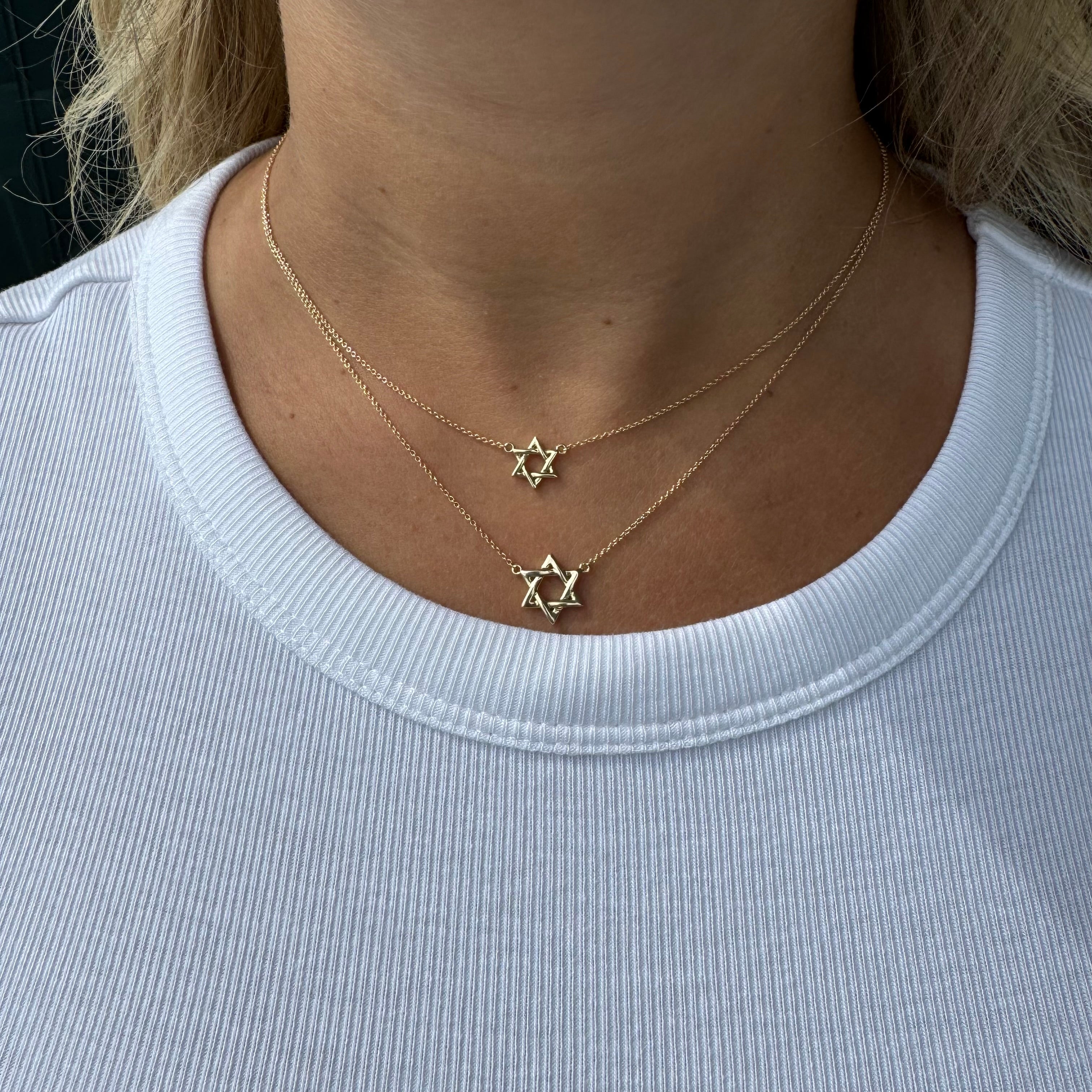 Woman wearing 14K Gold Star Of David Necklace in layered style, showcasing protection and faith with elegant Hebrew nameplate.