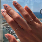 Elegant 18K gold chain ring featuring a birthstone, showcased on manicured hands with unique nail art by the seaside.