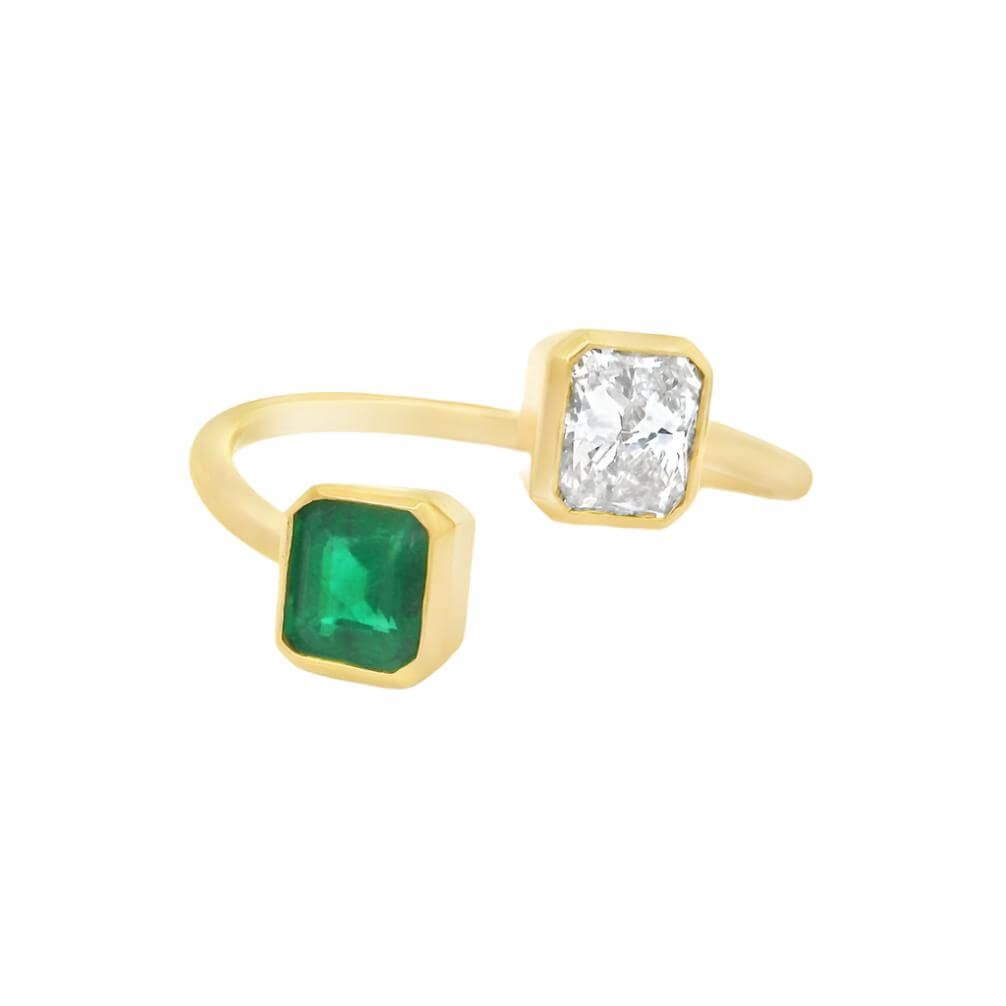 18K gold Toi et Moi ring featuring radiant cut diamond and emerald, elegant wrap design showcasing luxury gemstones.