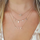 Layered 18K gold necklaces featuring zodiac constellations, celestial charms, and diamonds on a model's neck.