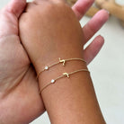 Mini Hebrew Initial Gemstone Bezel Bracelet worn on wrist with gold chain and delicate embellishments from Izakov Fine Jewelry.
