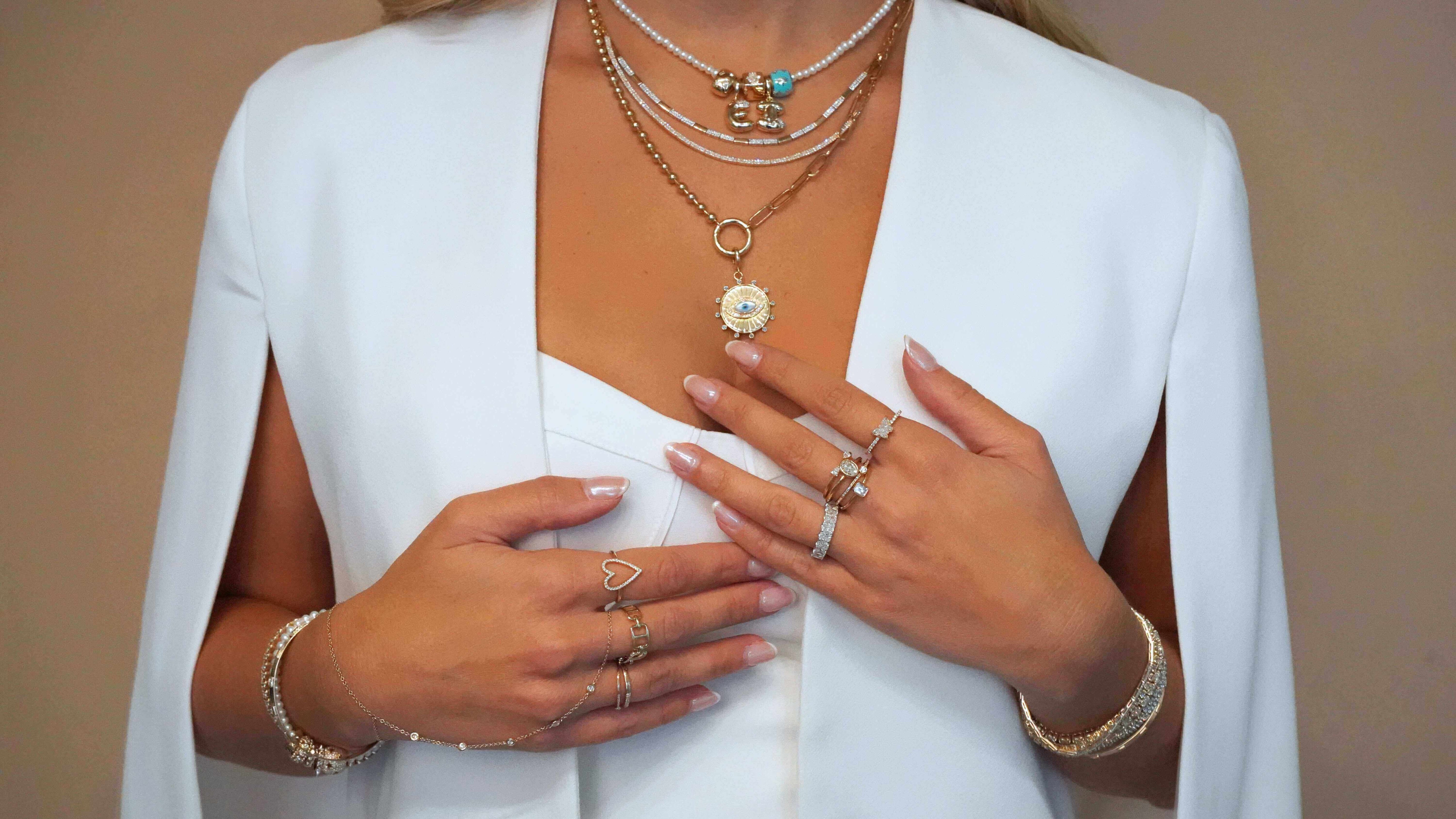 Izakov model wearing multiple pieces of jewelry including necklaces, rings, and bracelets on a plain background