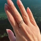 Personalized Script Duo Names Diamond Ring with pavé diamonds on a hand against a scenic background.