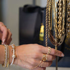 Woman showcasing a variety of gold jewelry including bracelets and chains, featuring the Pearl Beaded Bracelet by Izakov Fine Jewelry.