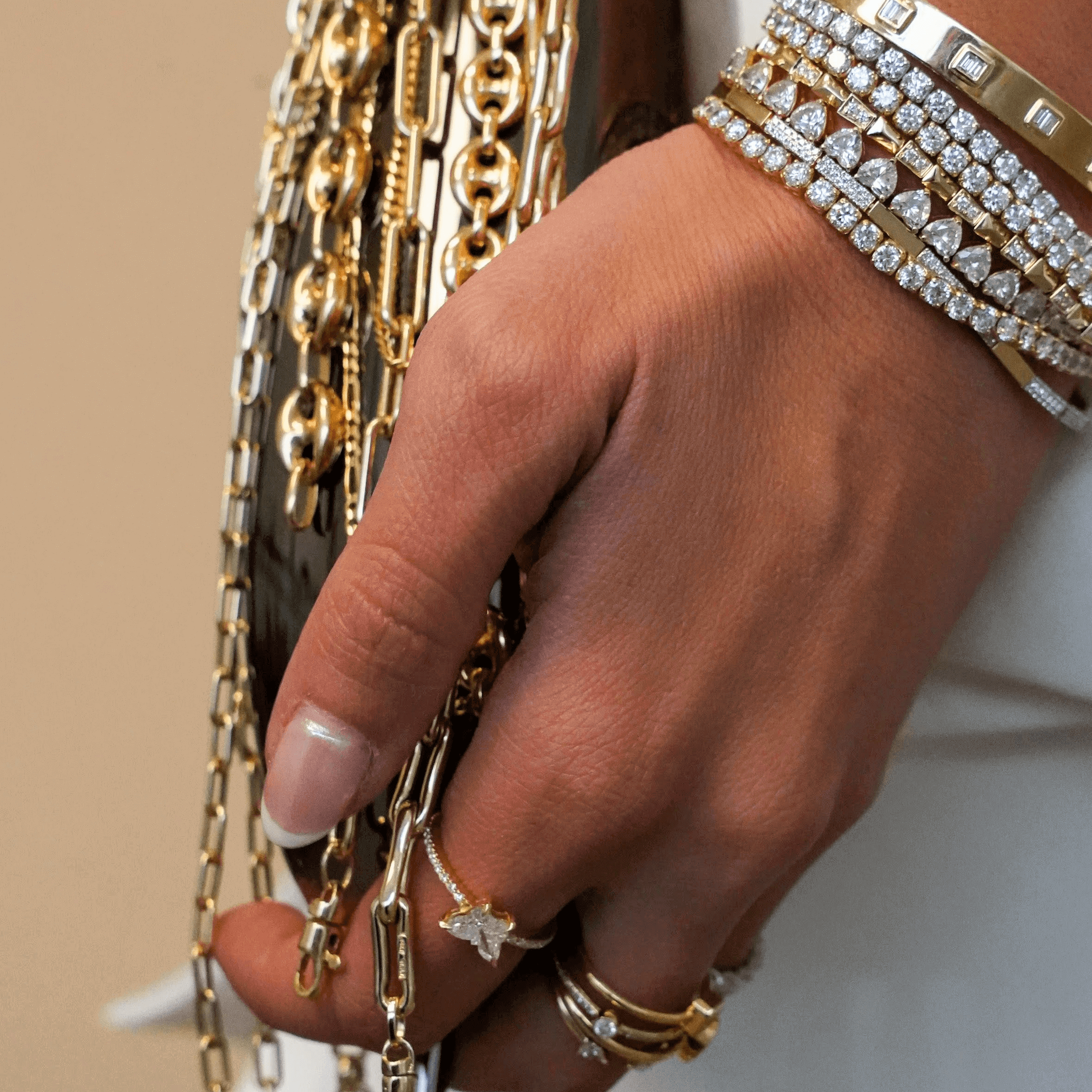 Close-up of a hand adorned with gold and diamond jewelry, featuring rings and sparkling bracelets.
