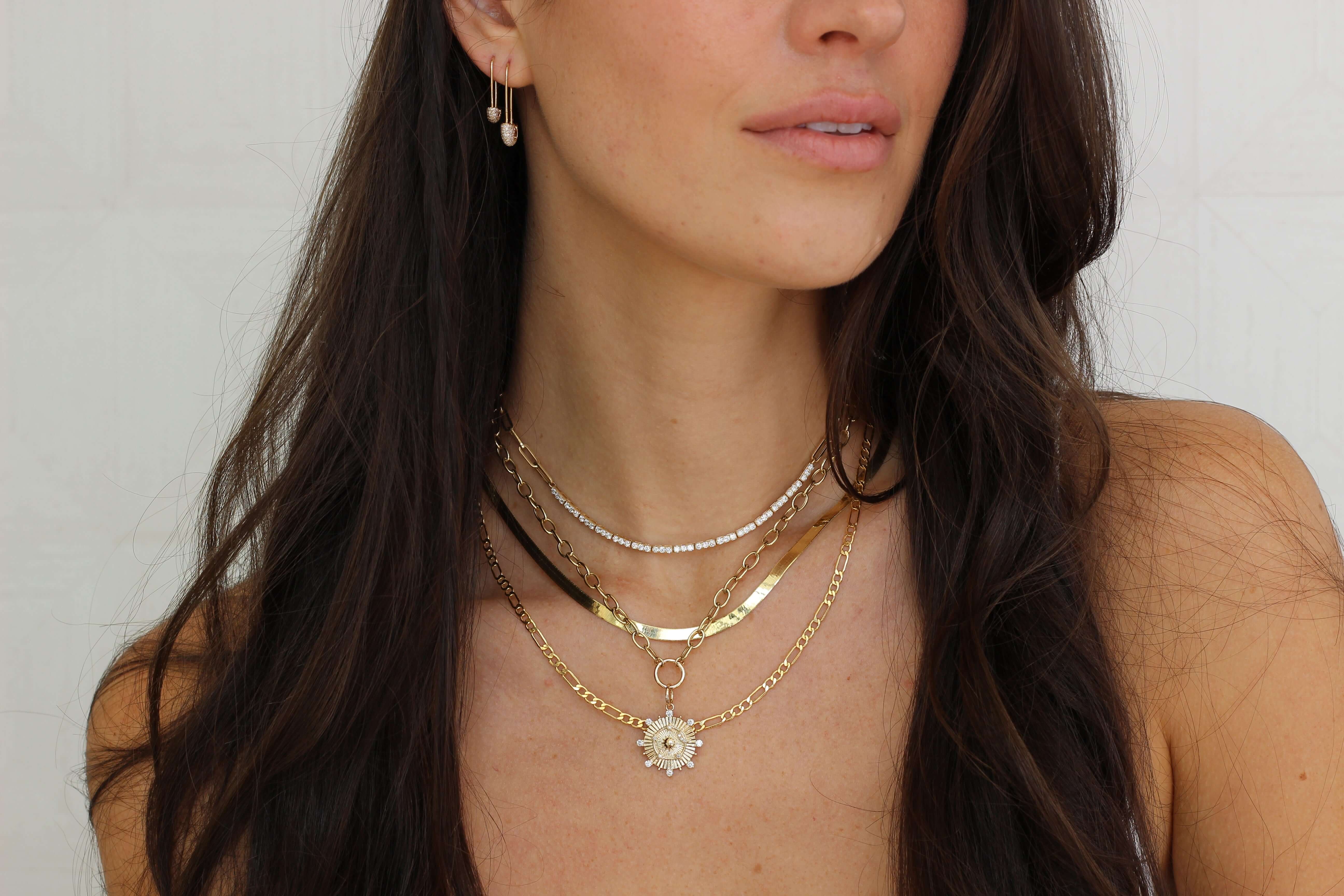 Woman wearing layered gold and silver necklaces with a pendant, showcasing elegant jewelry from our collection