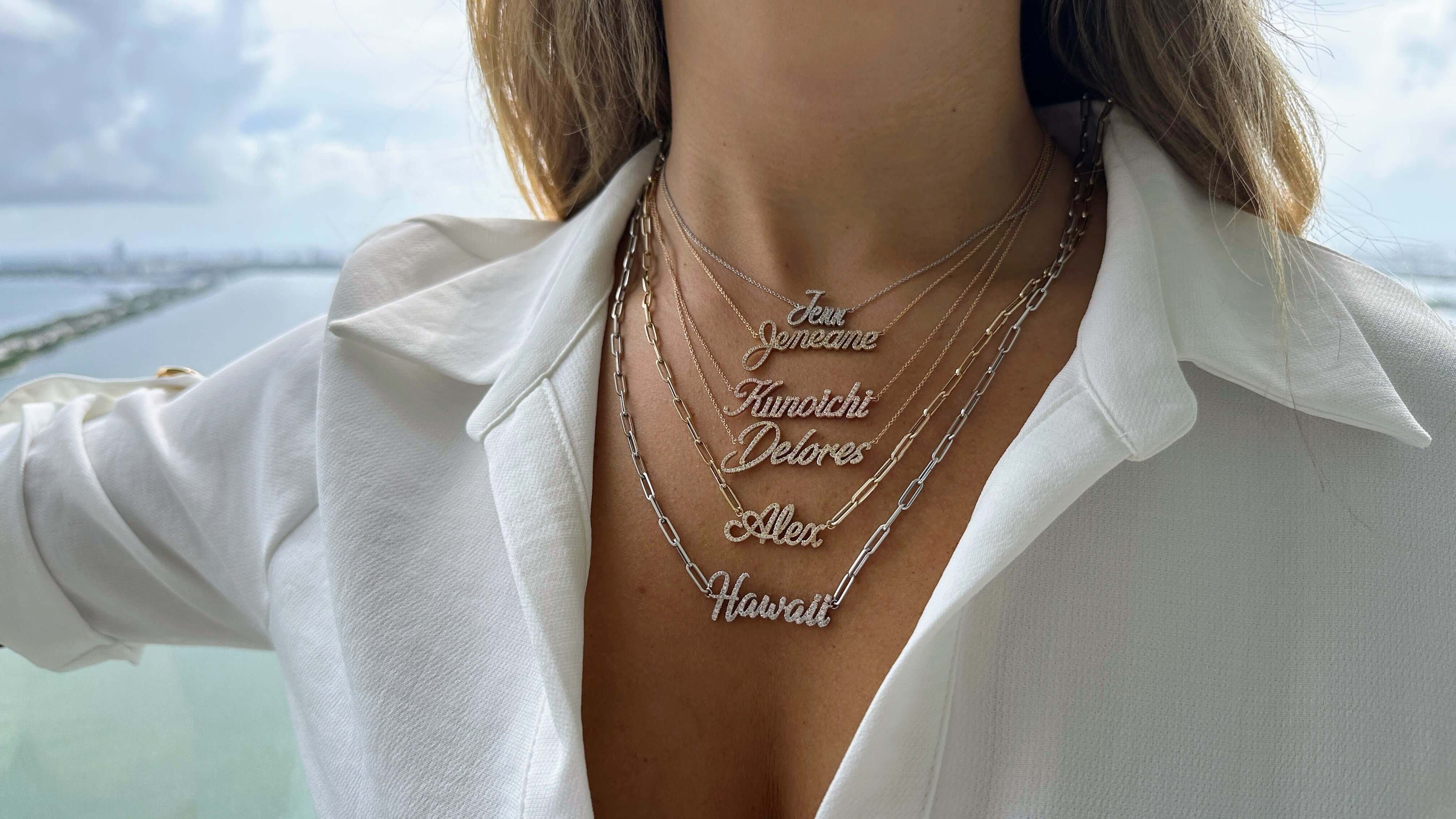 Woman showing layered necklaces with custom name pendants from our jewelry collection.