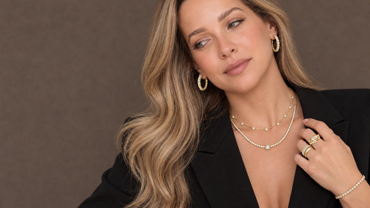 Model wearing Izakov 14K gold diamond hoops, station and tennis necklaces, rings and bracelet