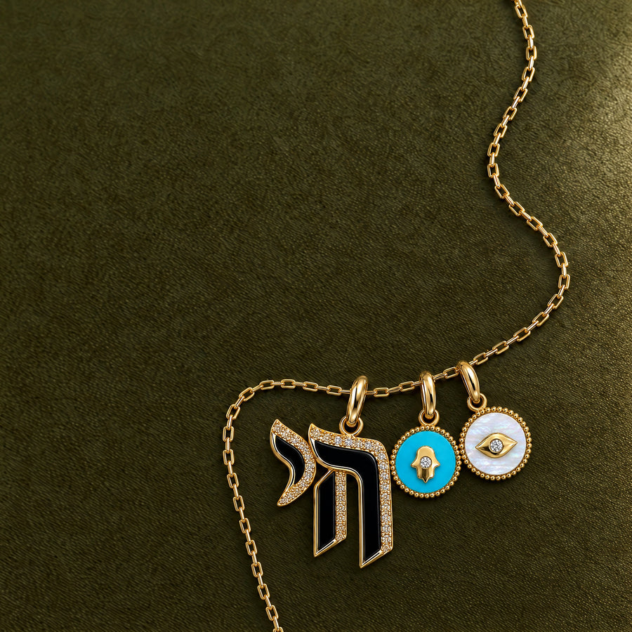 Gold chai, hamsa and evil eye charms on a gold chain, on olive velvet