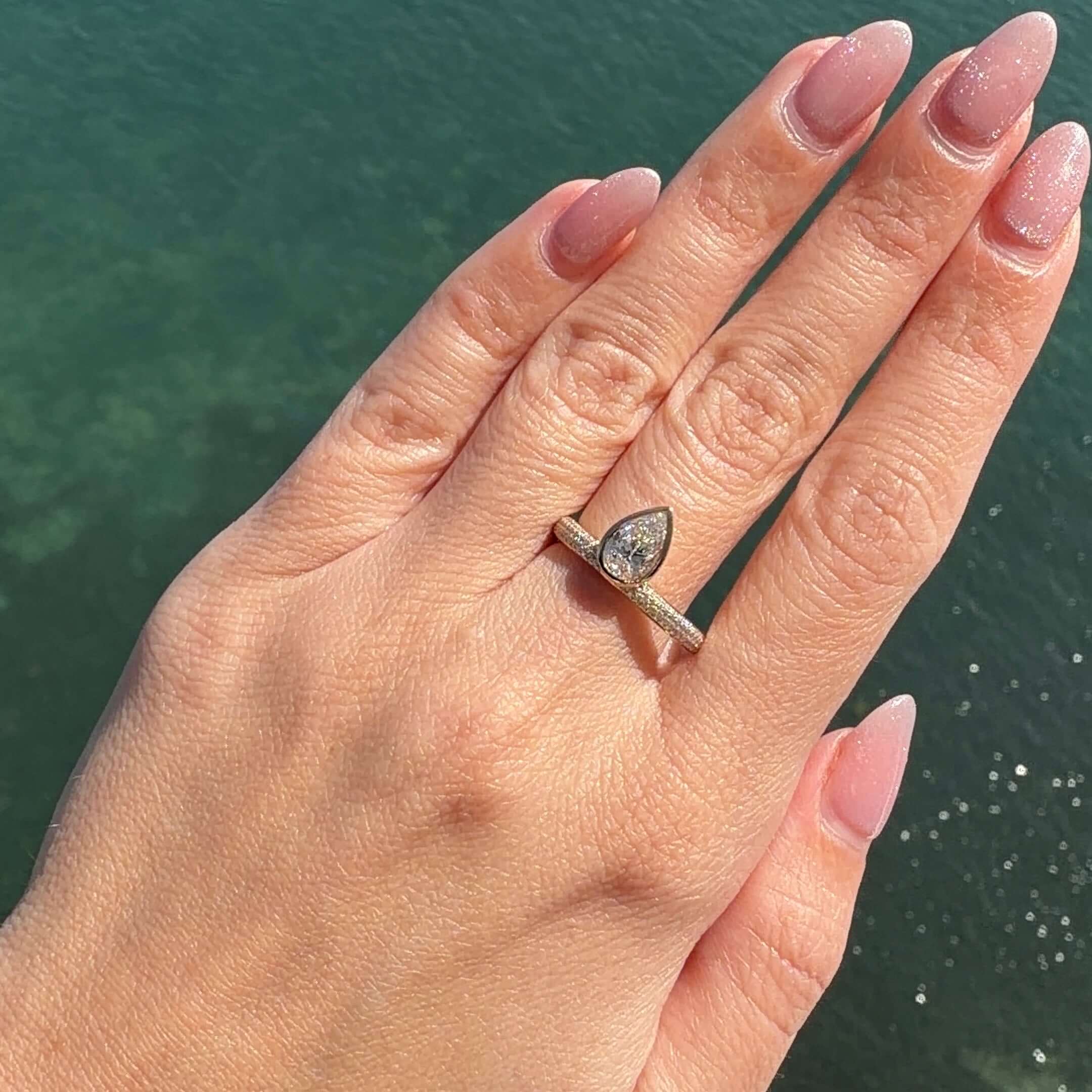 Bezel Lab Diamond Micro Pave Ring shown on a hand, featuring a pear-shaped lab diamond in 14k gold.