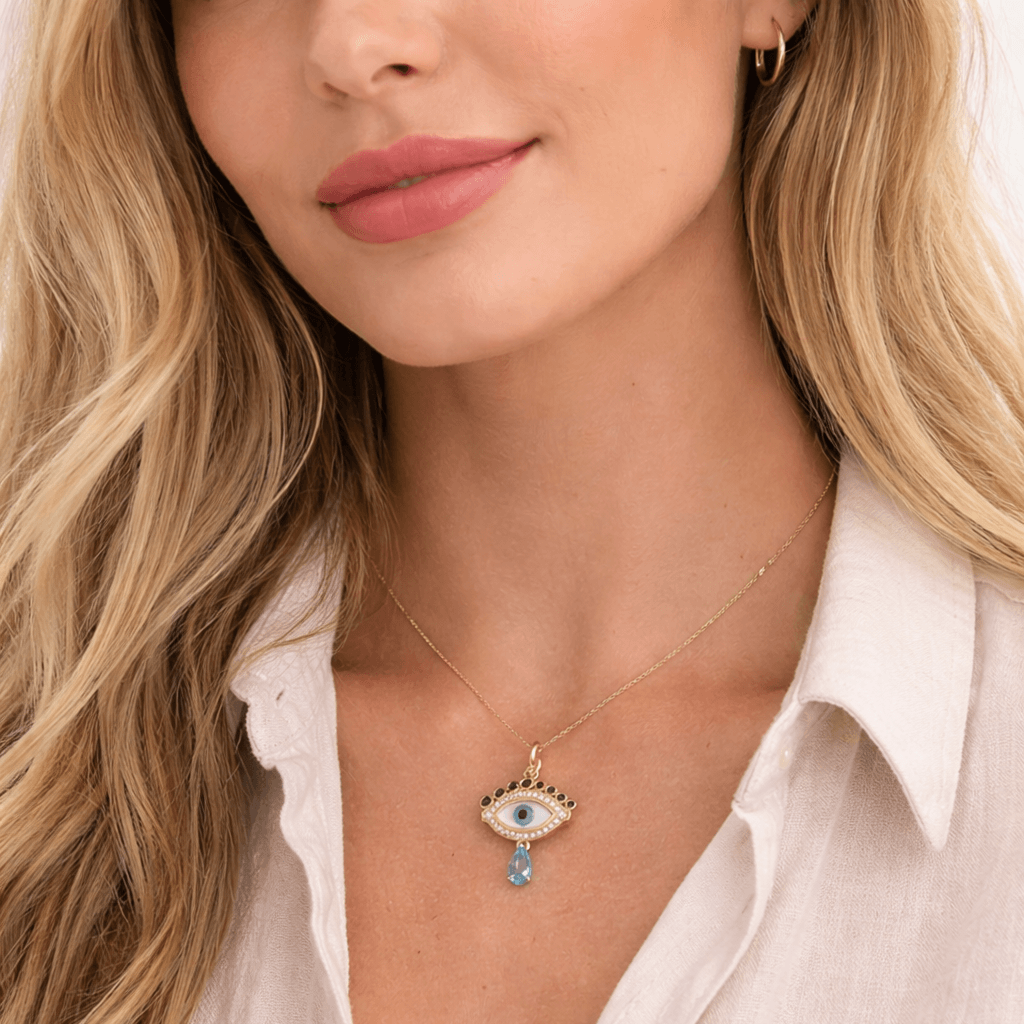 Celestial Evil Eye Diamond Charm worn by a woman, featuring mother of pearl and blue topaz accents in 14k gold.