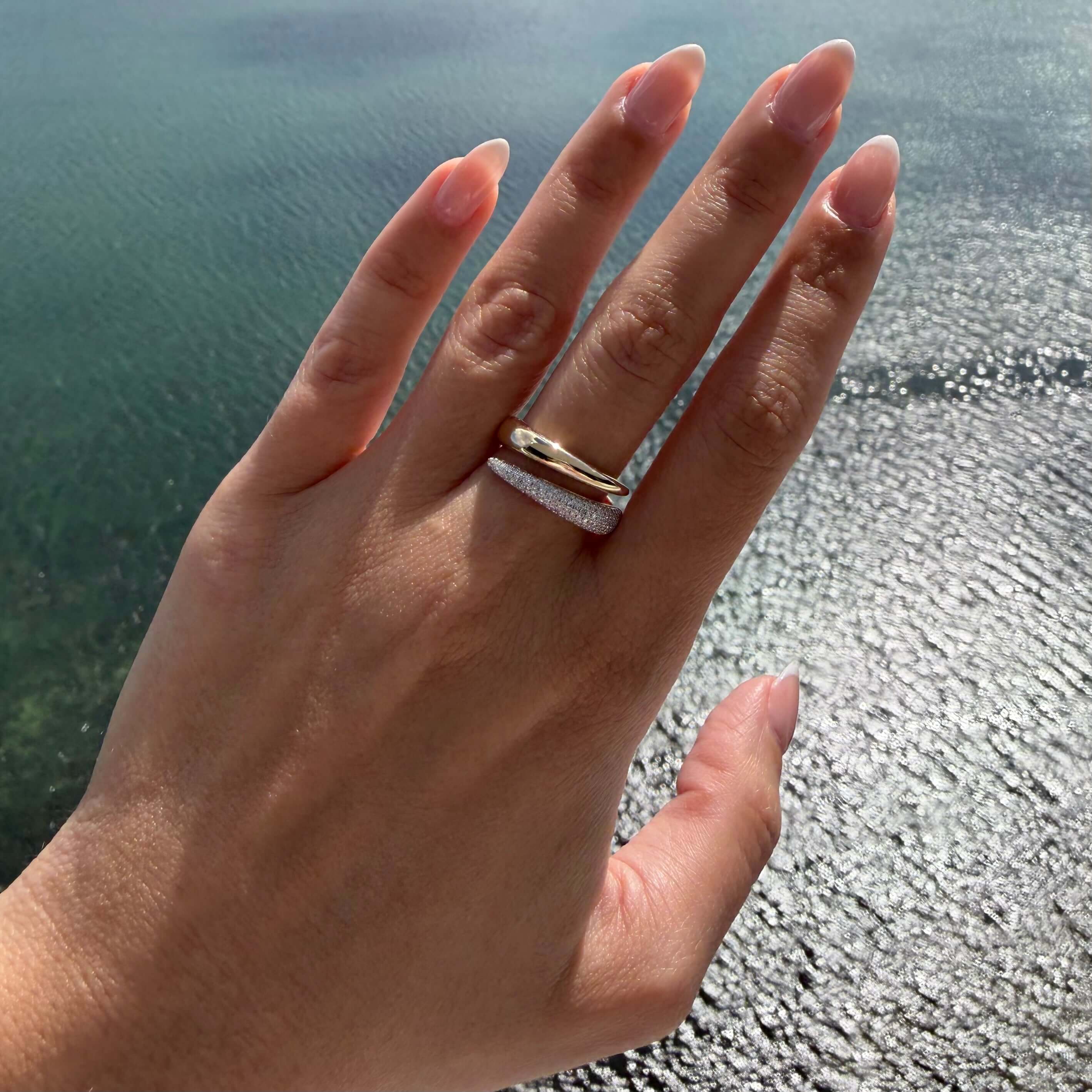 Diamond Pavé Split Wrap Ring displayed on a hand over shimmering water background.