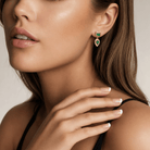 Close-up of a model wearing Emerald Ripple Drop Earrings in 14k Yellow Gold with rich green emeralds.