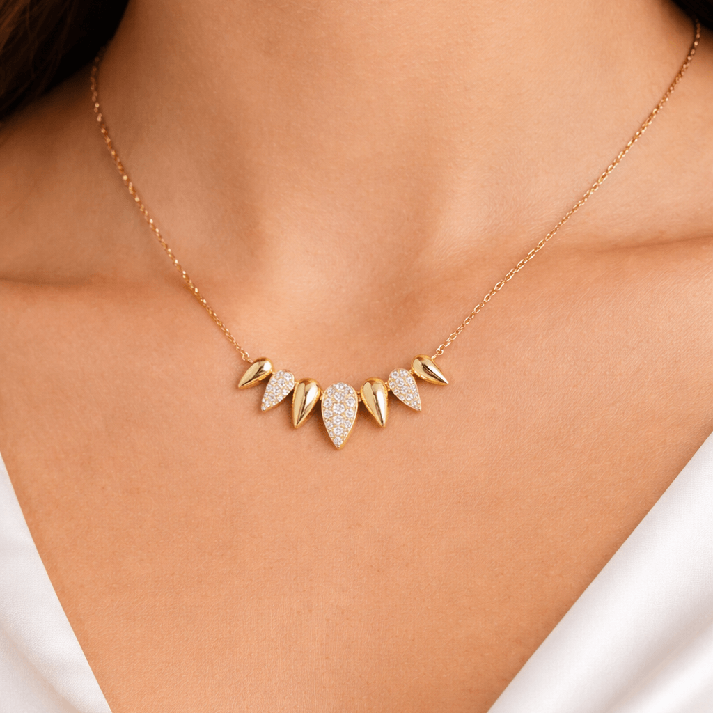 Graduated Diamond Teardrop Necklace showcasing polished gold and diamond pavé accents on a model's neck.