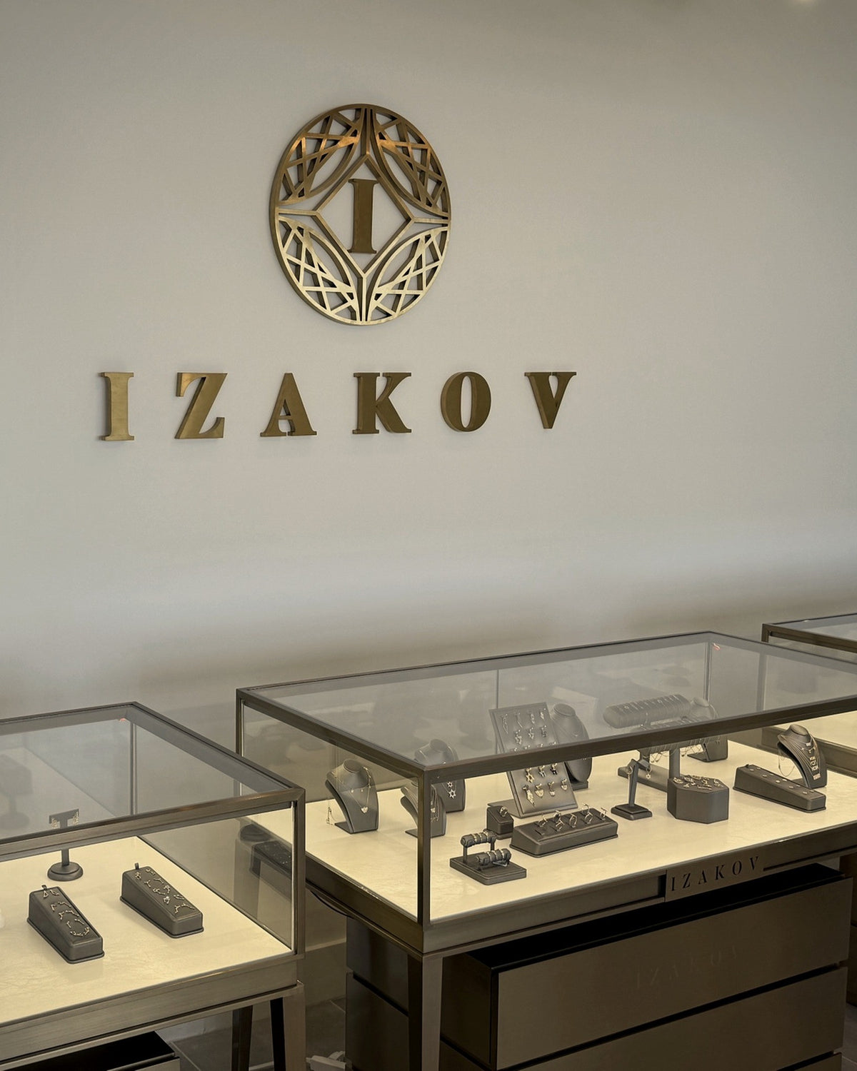 Izakov Fine Jewelry showroom in Miami with brass logo and glass display cases