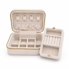An open cream-colored velvet jewelry organizer case with gold-tone zipper trim, shown alongside its matching inner lid tray on a clean white background.