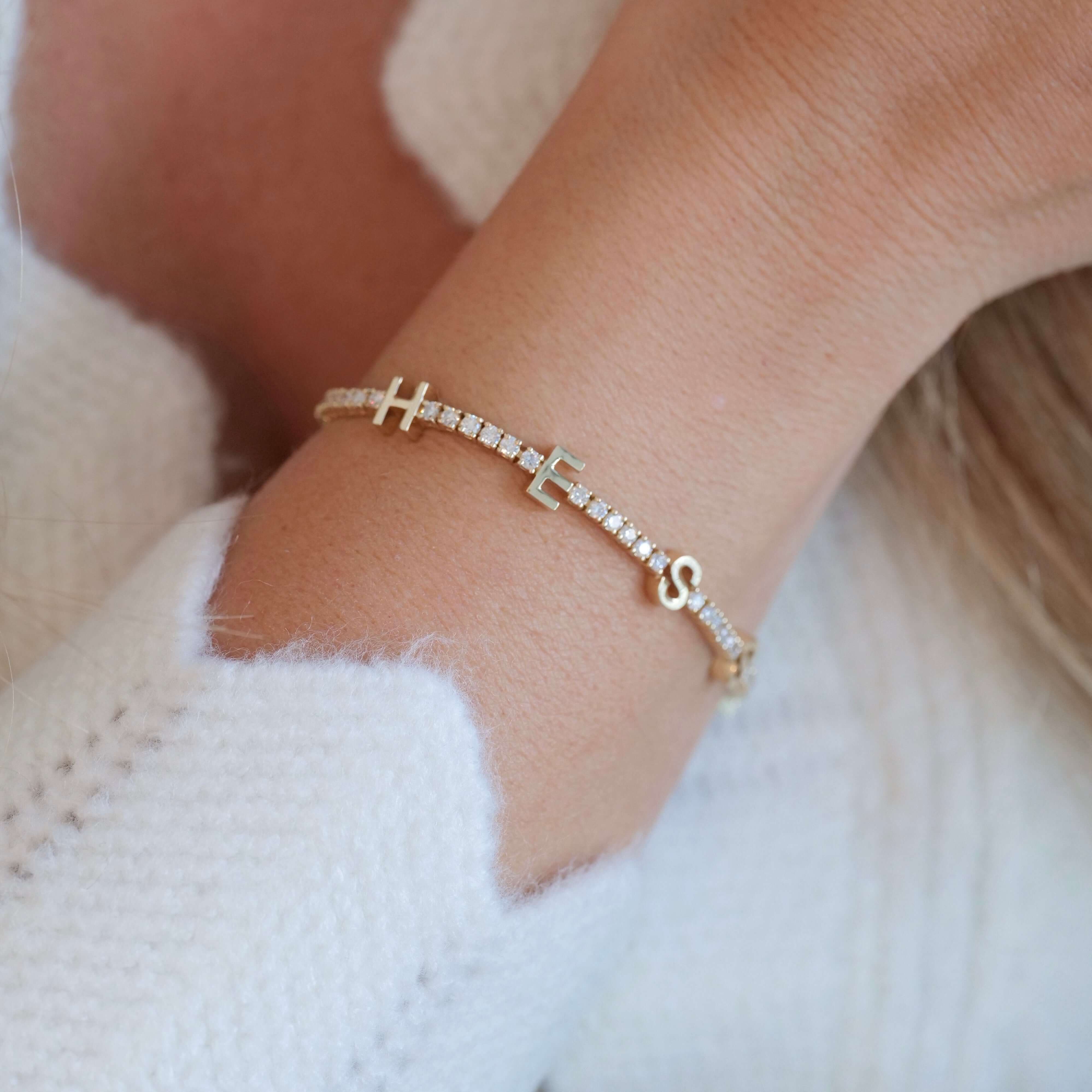Personalized Station Block Name Diamond Tennis Bracelet worn on wrist, showcasing sparkling diamonds and gold design.