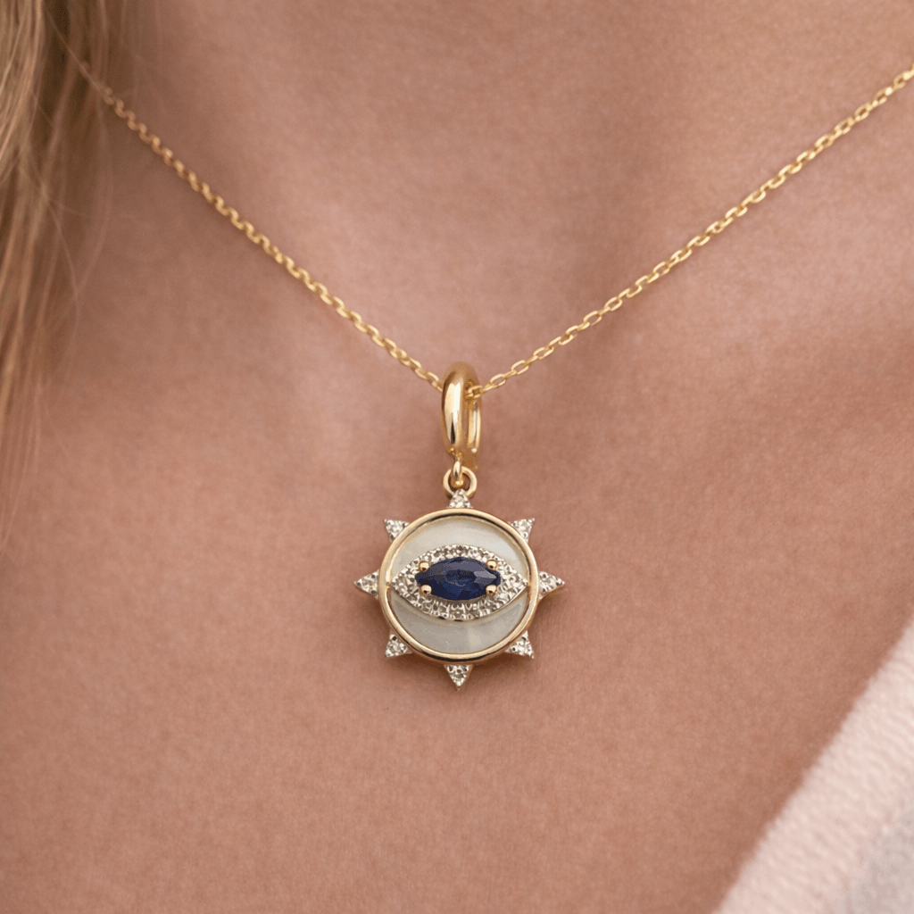 Petite Sapphire Evil Eye Diamond Coin Charm worn as a pendant on a gold chain against a bare neck.