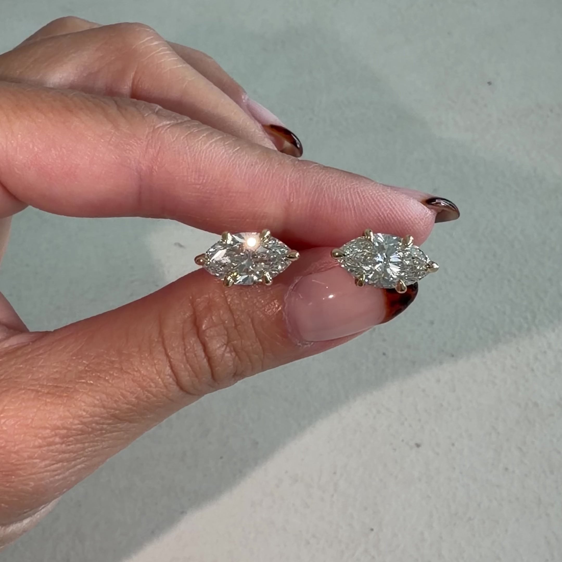 Lab-Grown Marquise Cut Diamond Stud Earrings held in hand, showcasing elegant design and sparkling diamonds.