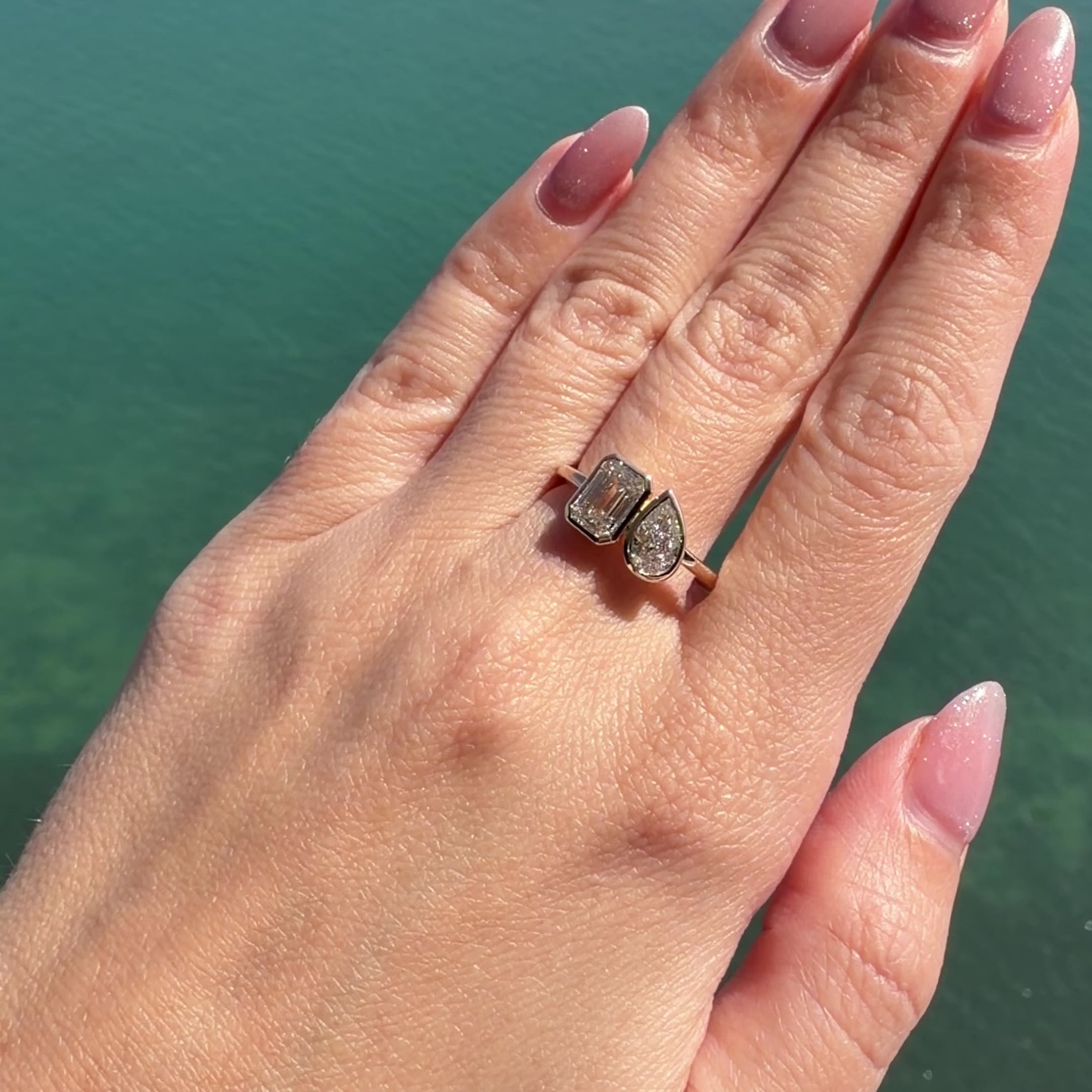 Lab Diamond Toi et Moi Bezel Ring worn on hand, featuring pear and emerald-cut lab diamonds in 14k gold.