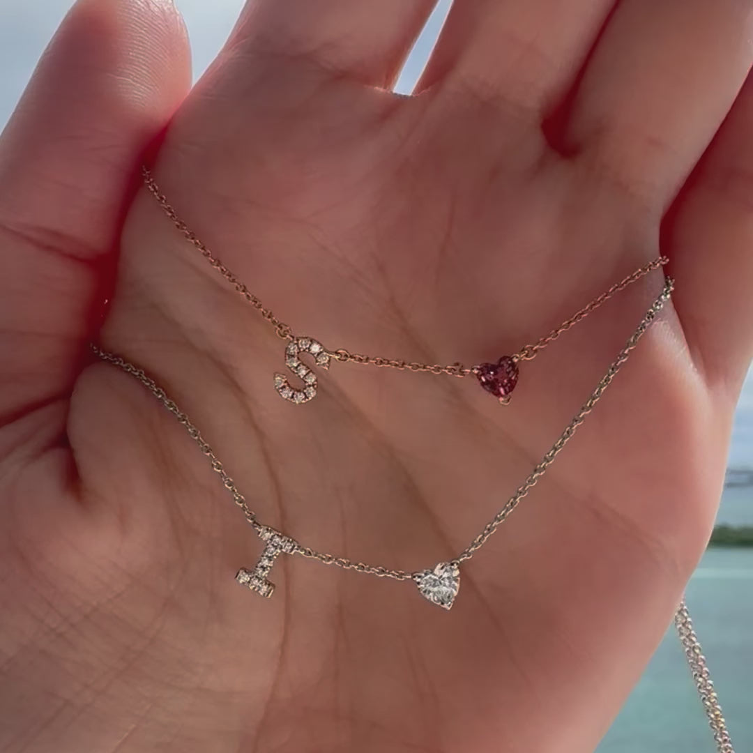 14K Gold Pave Diamond Initial Heart Gemstone Necklace with sparkling letters and heart pendants displayed on a hand.