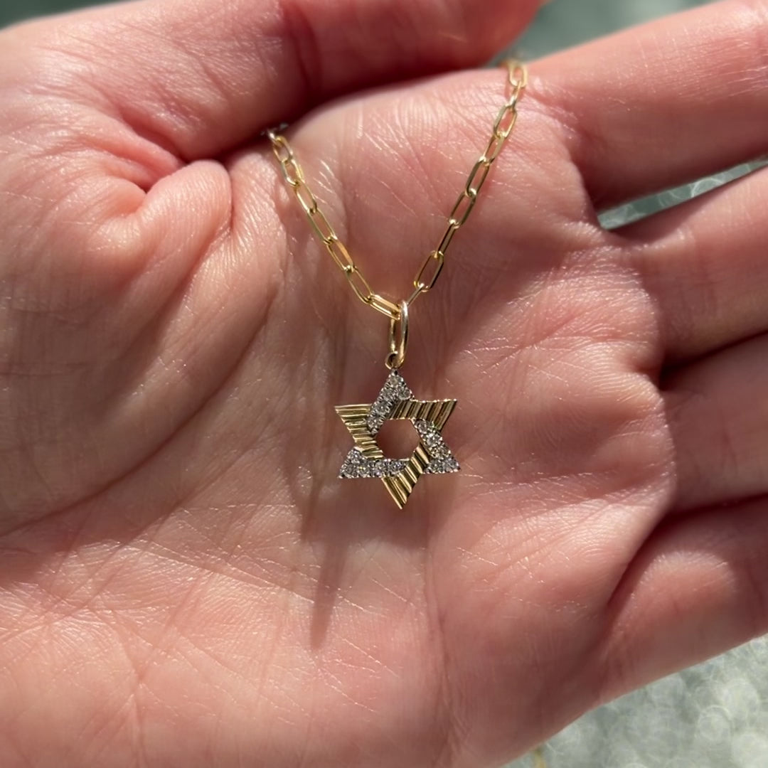 Radiating Star of David Diamond Pendant showcased in hand with gold chain and diamond details.