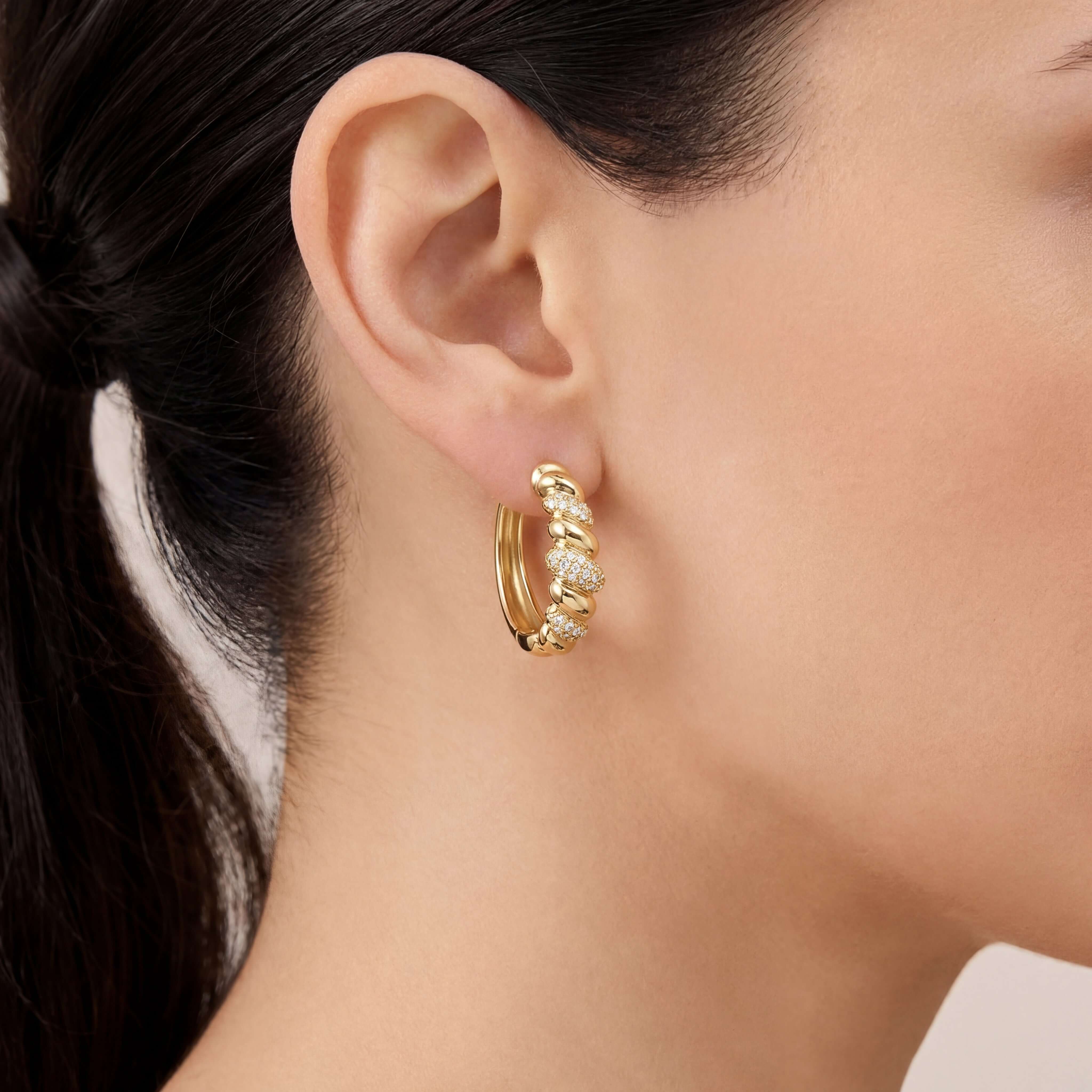 Twisted Diamond Pave Hoop Earrings showcased in a close-up of a model's ear, highlighting sparkling pavé diamonds.
