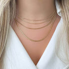 Woman wearing layered gold chain necklaces from our jewelry collection.