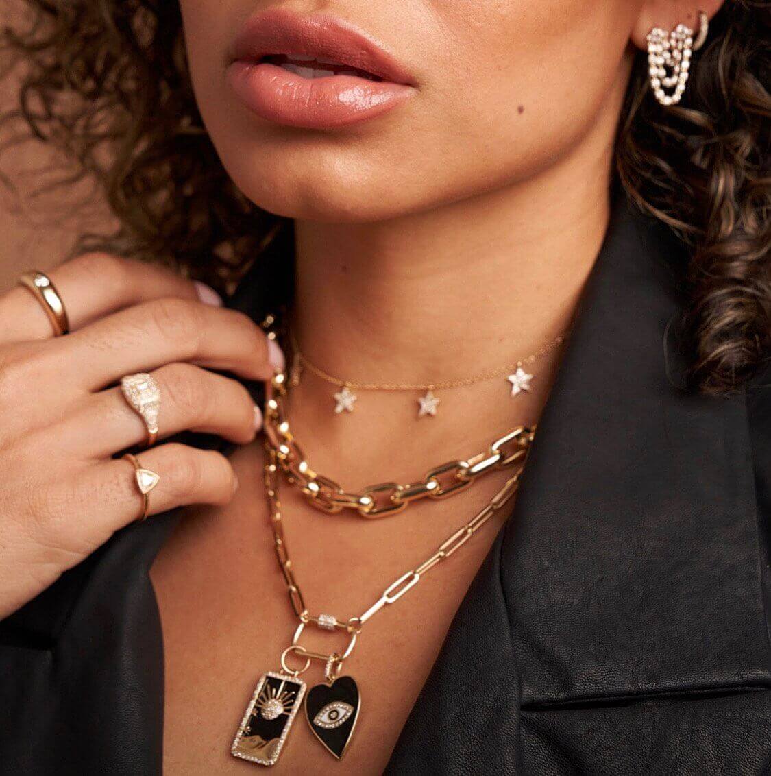 Woman wearing layered gold necklaces with celestial charms, matching star choker, elegant rings, and pearl earrings from our jewelry collection